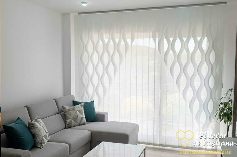 Sala de estar: cortina vertical blanca con diseño de ondas tridimensionales grandes, sofá chaise longue gris, cojines turquesa y mesa de centro de vidrio.