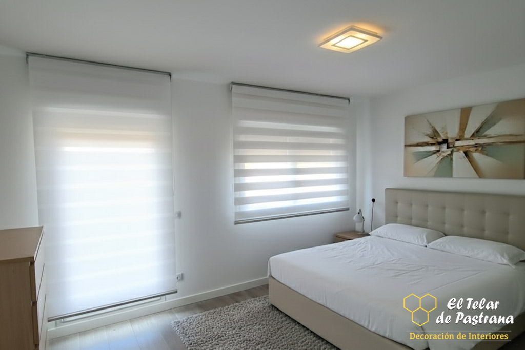 Dormitorio moderno y luminoso con estores noche y día blancos instalados en ventana y puerta acristalada, control de luz y privacidad