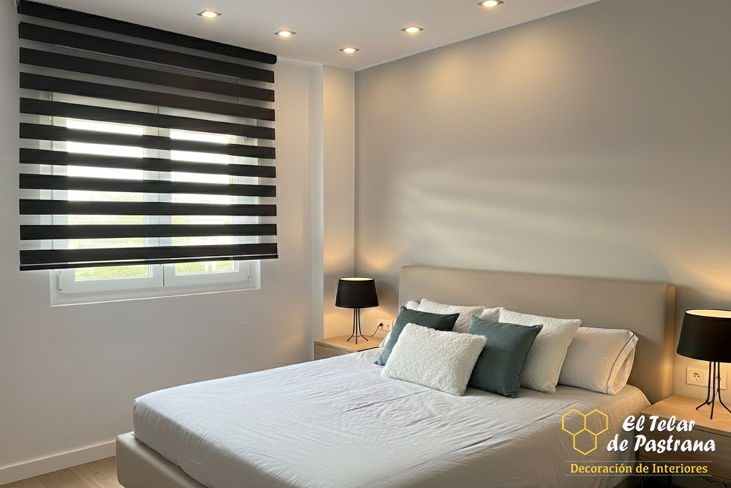 Dormitorio moderno con estor noche y día en color negro, cama tapizada y luz natural controlada