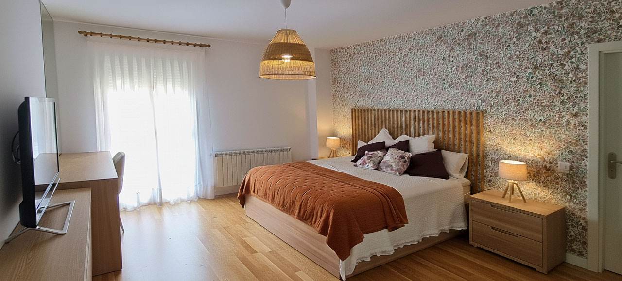 Dormitorio de diseño con cortinas visillo a medida y papel pintado de líneas finas. Instalación profesional de El Telar de Pastrana.